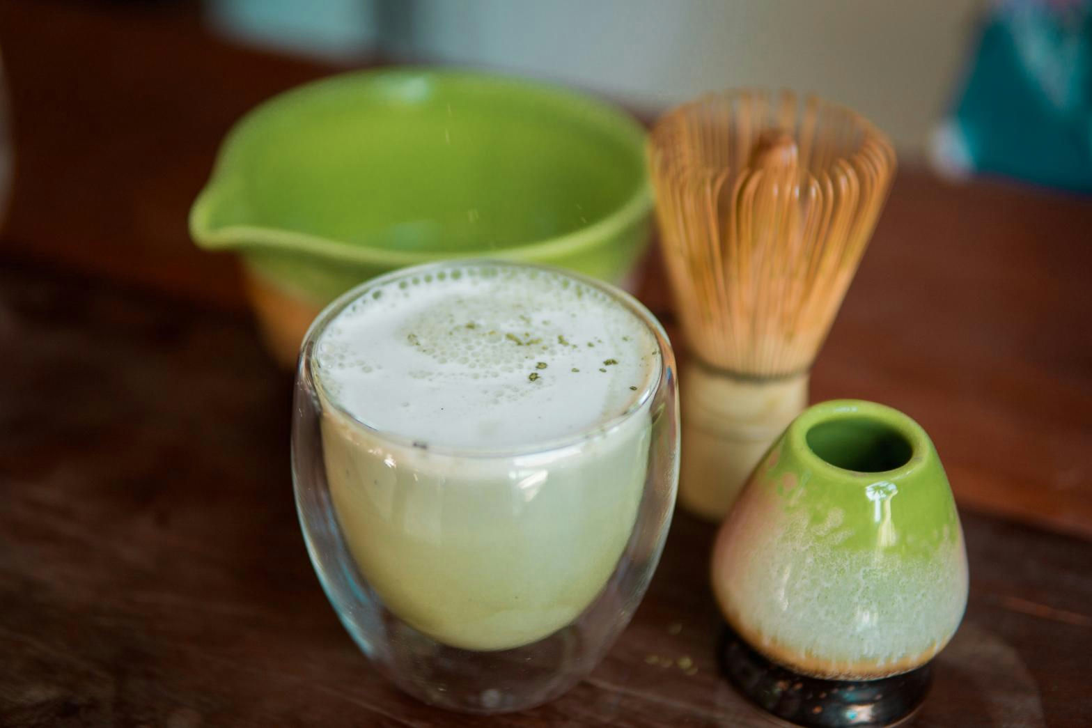 Frothy matcha latte with bamboo whisk at The Shala Grounds cafe at Kahana Baler