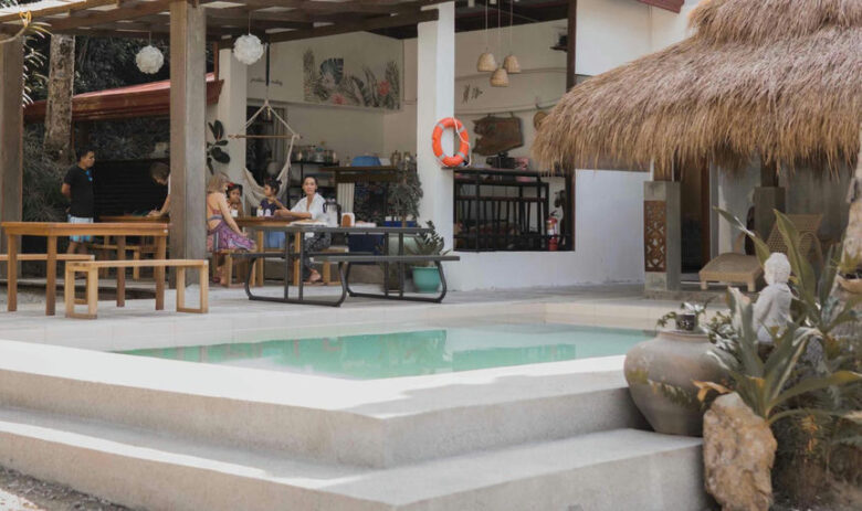 A small pool and covered outdoor dining area with a thatched roof and hammock at Kahana Baler in Cemento, Baler.