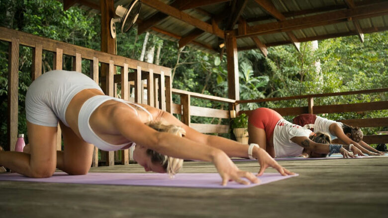 Group practicing yoga stretches on an open-air wooden deck at Kahana Baler, Cemento, Baler