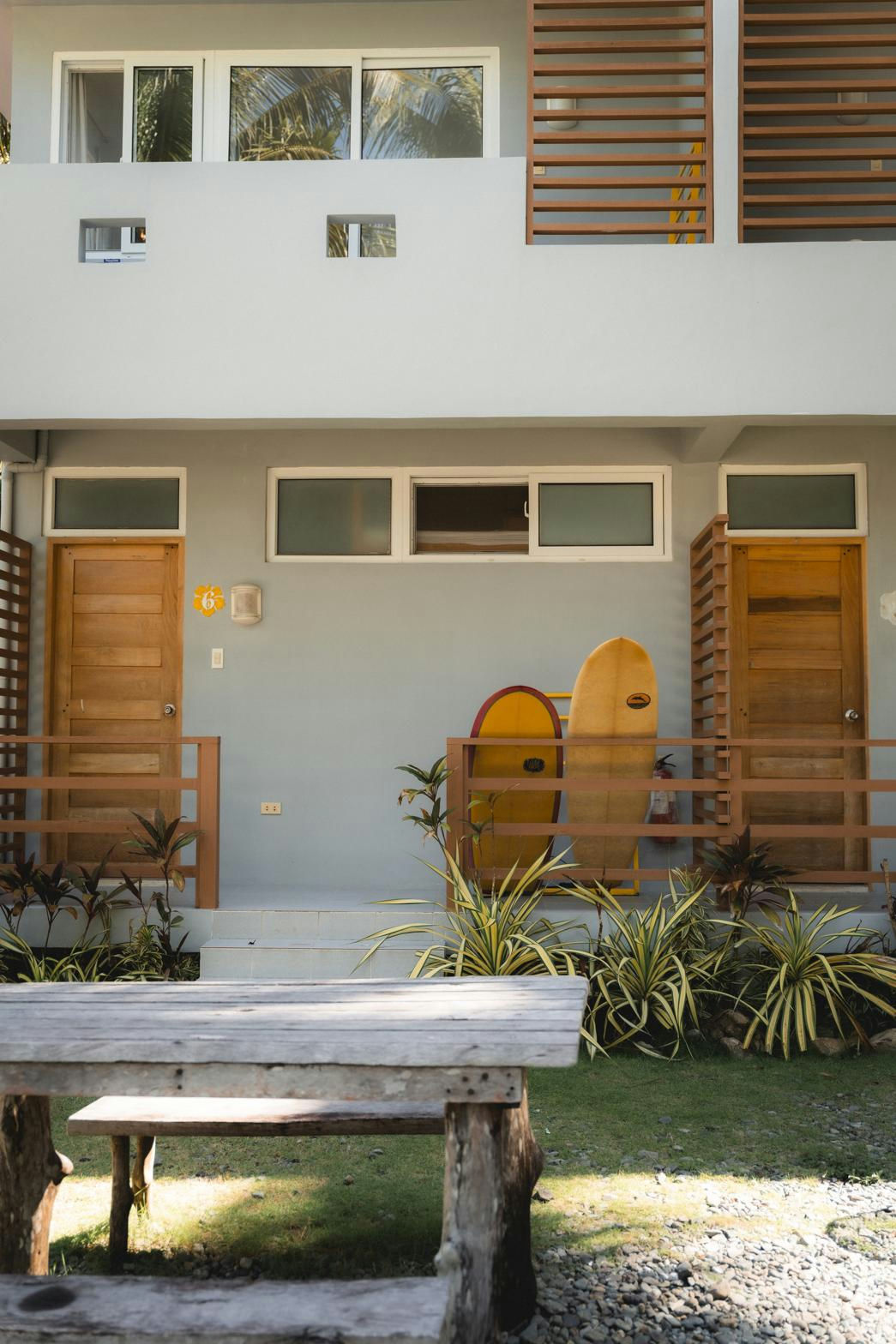 Yellow and red surfboards leaning against the exterior of the Kahana Baler surf and workation bed and breakfast in Cemento, Baler